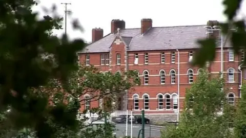 A screengrab of TV footage of St Colman's College, Newry.  A large, ornate, three-storey red brick building is partially visiable behind trees.  A number of cars are parked in front of the school.