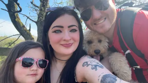 Family handout Rebecca and Anthony are posing for a selfie with his daughter and their dog in a park. 