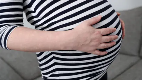 BBC A woman holding her bump