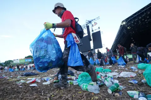 BBC A man with a bin bag clears litter at Glastonbury
