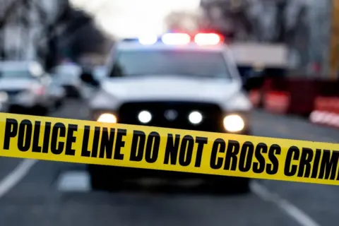 Getty Images Police tape is seen in front of a police vehicle 