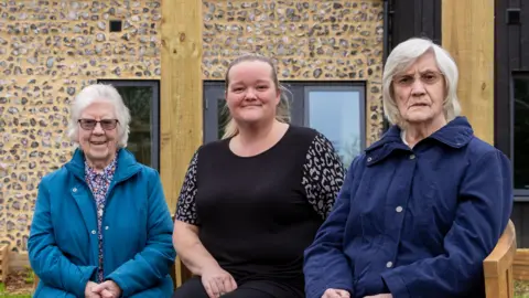Healthcare Management Trust Two elderly women sat beside a younger woman