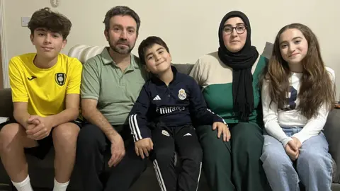 The Olmez family sitting together on their sofa