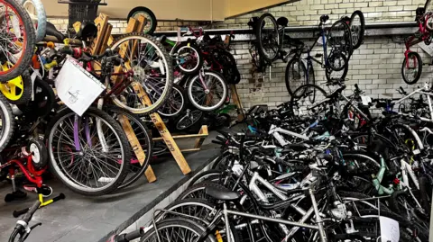 A workshop full of bicycles hanging floor to ceiling.