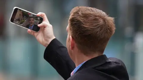 PA Media Alex Belfield to take a picture of himself outside the Nottingham Crown Court during his trial in July 2022.