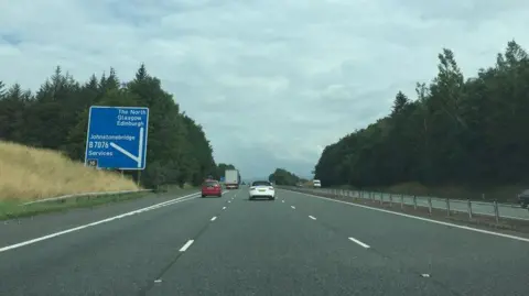 The A74(M) motorway with a few cars on it and a sign for Glasgow and the North and Johnstonebridge services