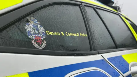 A picture of a green and blue police car. There is a logo on the side with the writing Devon & Cornwall Police.