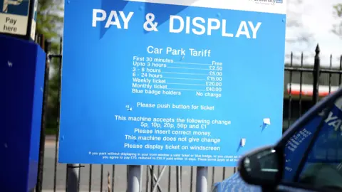 A Pay & Display blue hospital parking tariff board with white writing for payment amount.