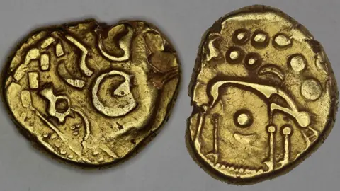 Trustees of the British Museum Two views of an Iron Ag gold stater. On the left it shows patterns struck in a die; on the right the design is of a stick figure of a wolf.
