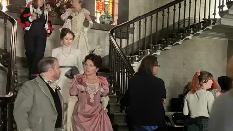 Cast in 19th century costumes assemble on location