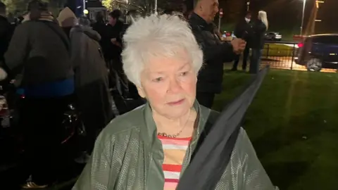 Kate Nash, a woman with grey hair, wearing a green jacket.