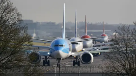 PA Media Four planes queuing up on a runway at Gatwick Airport.