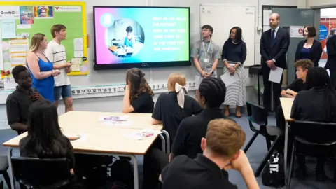 Danny Lawson/PA Wire Prince William is stood in a classroom at Meadowhead School, surrounded by members of staff and students who are sat at their desks, watching a presentation on an electronic whiteboard.