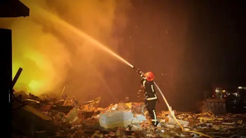 A firefighter extinguishes a building fire in Khmelnytskyi, Ukraine, in February 2023, in a photo provided by state rescue services.