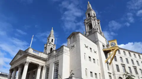 Leeds Civic building - a large white building with column and a large golden clock on the side.