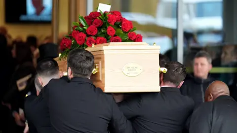PA Media The coffin of John Robertson is carried into Rushcliffe Oaks Crematorium, Nottingham.