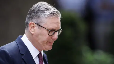 EPA/Shutterstock A man, Keir Starmer, wearing a dark blue suit and burgundy tie.