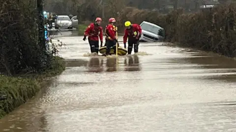 Essex County Fire and Rescue Service Firefighters pulling a small boat in floodwater 