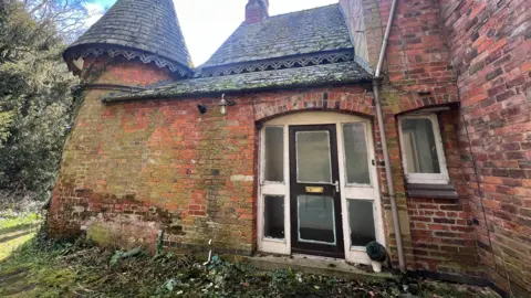 Old crumbling outer building with moss on walls on park grounds