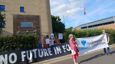 Bucks Council Stop Funding Fossil Fuels A group from 'Bucks Council Stop Funding Fossil Fuels' hold banners outside Buckinghamshire Council offices on a sunny Sunday in June 2025.