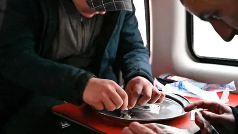 man in hat taking drugs from a silver plate