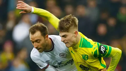 Reuters Brandon Williams (derecha) en el amarillo y el verde de Norwich City retiene al Christian Eriksen de Bremtfprd, que está en una franja blanca.