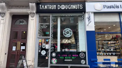 Tantrum Doughnut's shop front. The signage is black and white with drawings of doughnuts.