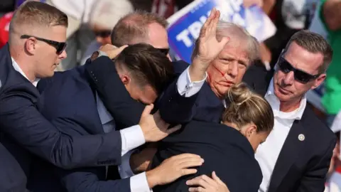 Reuters Donald Trump surrounded by Secret Service agents after being shot in the ear