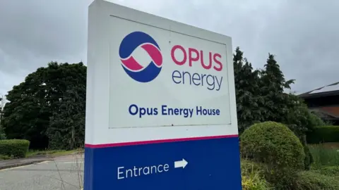 Ollie Conopo/BBC Large blue and white entrance sign for Opus Energy House, surrounded by trees and shrubs