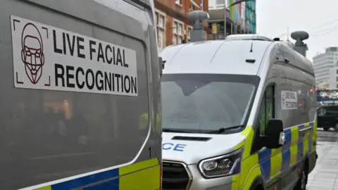 Two police live facial recognition vans are parked on a high street