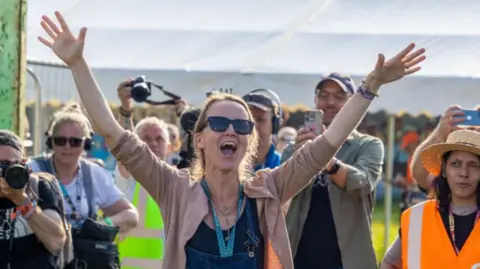Emily Eavis shouts a greeting to festivalgoers as she opens the gates to Glastonbury