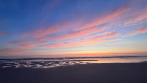 Maria MacPhee Pink and blue sunset reflected across wet beach sand.