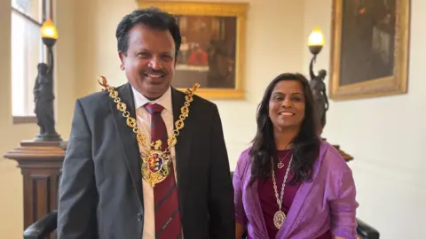 Jon Wright/BBC Elango and Manchula Elavalakan wearing civic medals, smiling