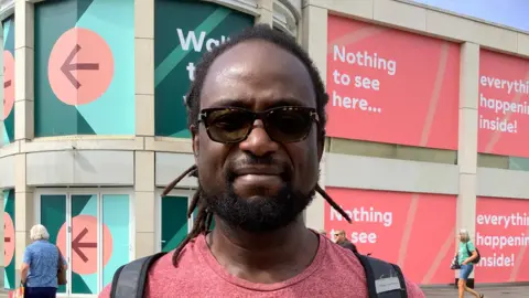 Laura Raymond / BBC A man wearing a red t-shirt with a backpack on.