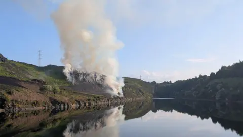 John Farquhar Smoke rises off a field by a river