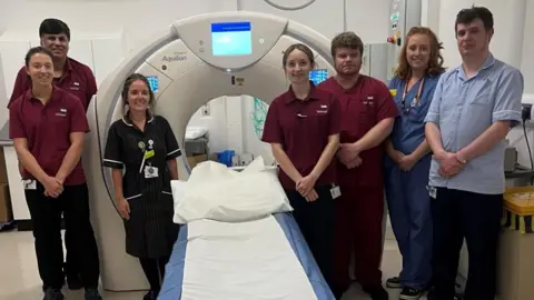 Nurses and staff standing next to a CT scan machine 