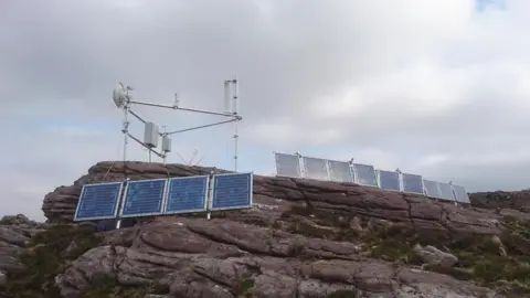 Highland Community Broadband Technology equipment on the top of a rocky hill. There are receivers and transmitters. 