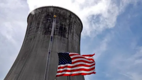 The US flag flies in front of a coal-fired power plant's cooling tower at Duke Energy's Crystal River Energy Complex in Crystal River, Florida