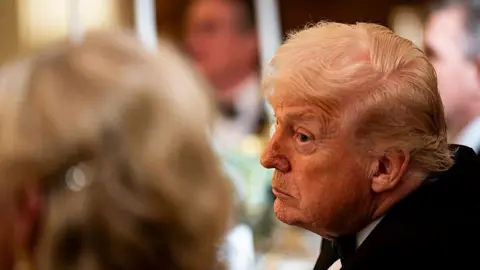 US President Donald Trump leans over to look at a fellow attendee of a black-tie event