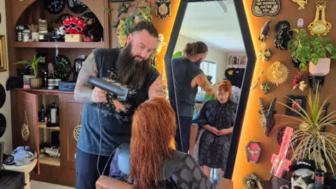 Simon Tuckwell blow-drying a client's hair at his Nottingham city centre salon.