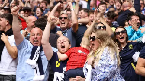Southend United fans - men, women and children - celebrating a goal at Wembley. 