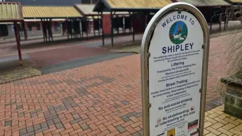 Aisha Iqbal/BBC A sign and market trader stalls in Shipley, Bradford.