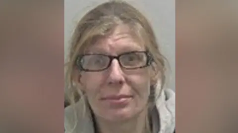 A woman with brown hair is in a portrait-shaped image in the middle of the photo. She is wearing dark glasses and a grey top.