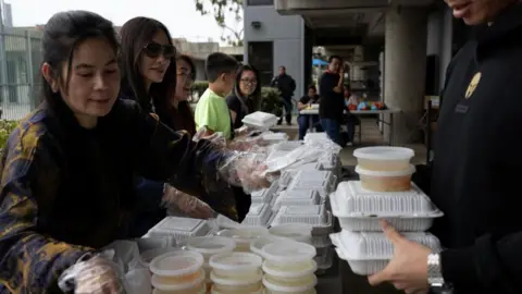 Reuters Several people organise parcels of food for distribution at an evacuation centre