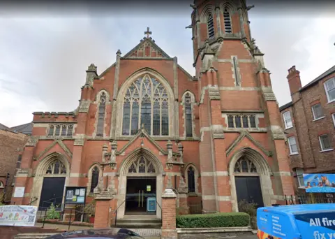 Google Red brick church building with cross and lerge stained-glass windows