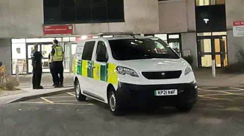 Police officers outside the A&E department at Aberdeen Royal Infirmary at night.