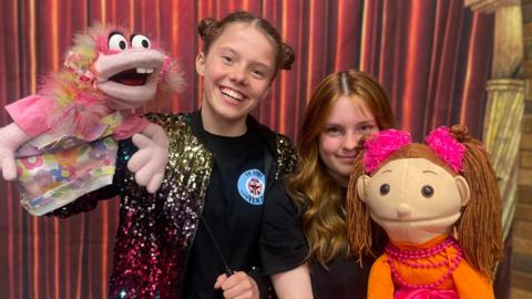 Teenage ventriloquists are smiling with their puppets
