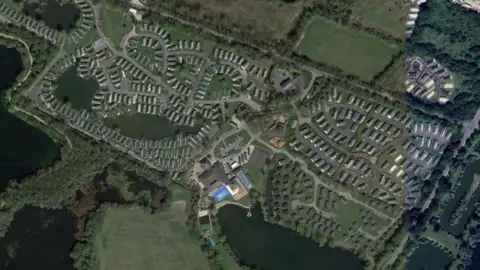 Google An aerial view taken from Google which shows the massive holiday park. It shows 65 acres of land with several lakes and bodies of water surrounding it. The rectangular site is dotted with hundreds of holiday cabins and there is the reception building and a pool in the centre.