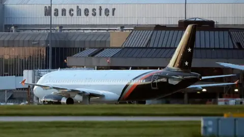 General view of an aircraft at Manchester Airport outside the grey terminal