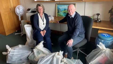 Wayne David and wife Jane, surrounded by full bin bags, clearing out his Westminster office